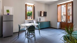 Eine moderne Küche mit Esstisch, Stühlen, einem Kühlschrank und einem an der Wand befestigten Fernseher.
