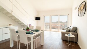 A modern apartment with a dining area, a sofa, and a TV mounted on the wall. - Lolita's Beachfront Loft by Wonderful Italy (Bari)