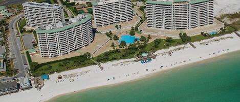 A coastal hotel complex with multiple high-rise buildings, a beach, and a swimming pool.