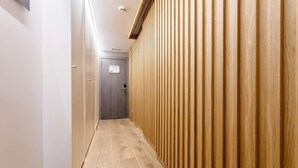 A narrow hallway with wooden paneling on one side and a door at the end.