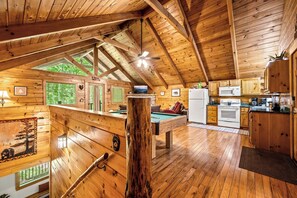 A wooden cabin interior with a pool table, kitchen area, and large windows. - Rustic 1BD Cabin w/ HOT TUB! Pool Table + Fire Pit (Sevierville)