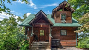 A log cabin with a green roof, a front porch, and a small porch area with a bench. - Relaxing 3BD Cabin w/ HOT TUB! Pool Table + GAMES! (Sevierville)