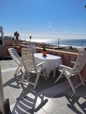 Enjoy a tranquil ocean view from this terrace, featuring a round table and four chairs.