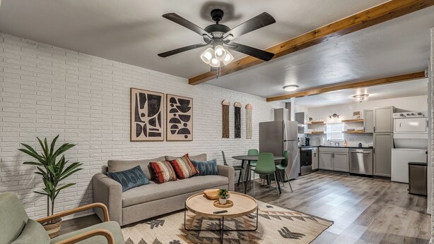 Una sala de estar moderna con sofá, mesa de centro y sillas, un comedor con mesa y sillas, y una cocina equipada.