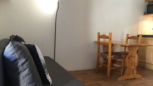 A living area with a sofa, a wooden dining table, and chairs.