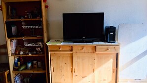 A room with a wooden cabinet, a television, and a clock on the wall.