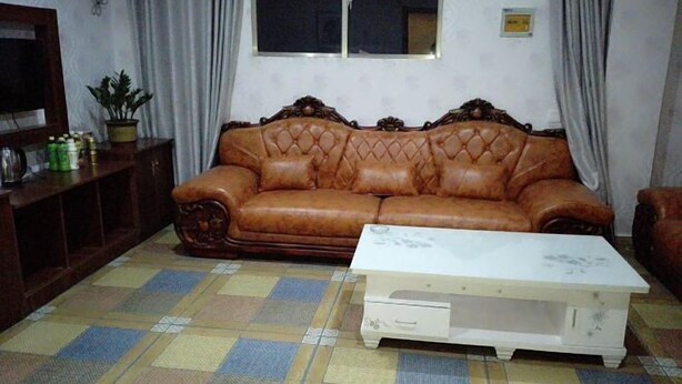 Una sala de estar con un sofá de cuero marrón, una mesita de centro blanca y un suelo con diseño.