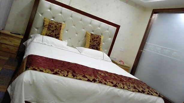 Ein ordentlich bezogenes Bett mit einer gesteppten Kopfteil, einer gemusterten Tagesdecke und zwei Zierkissen.