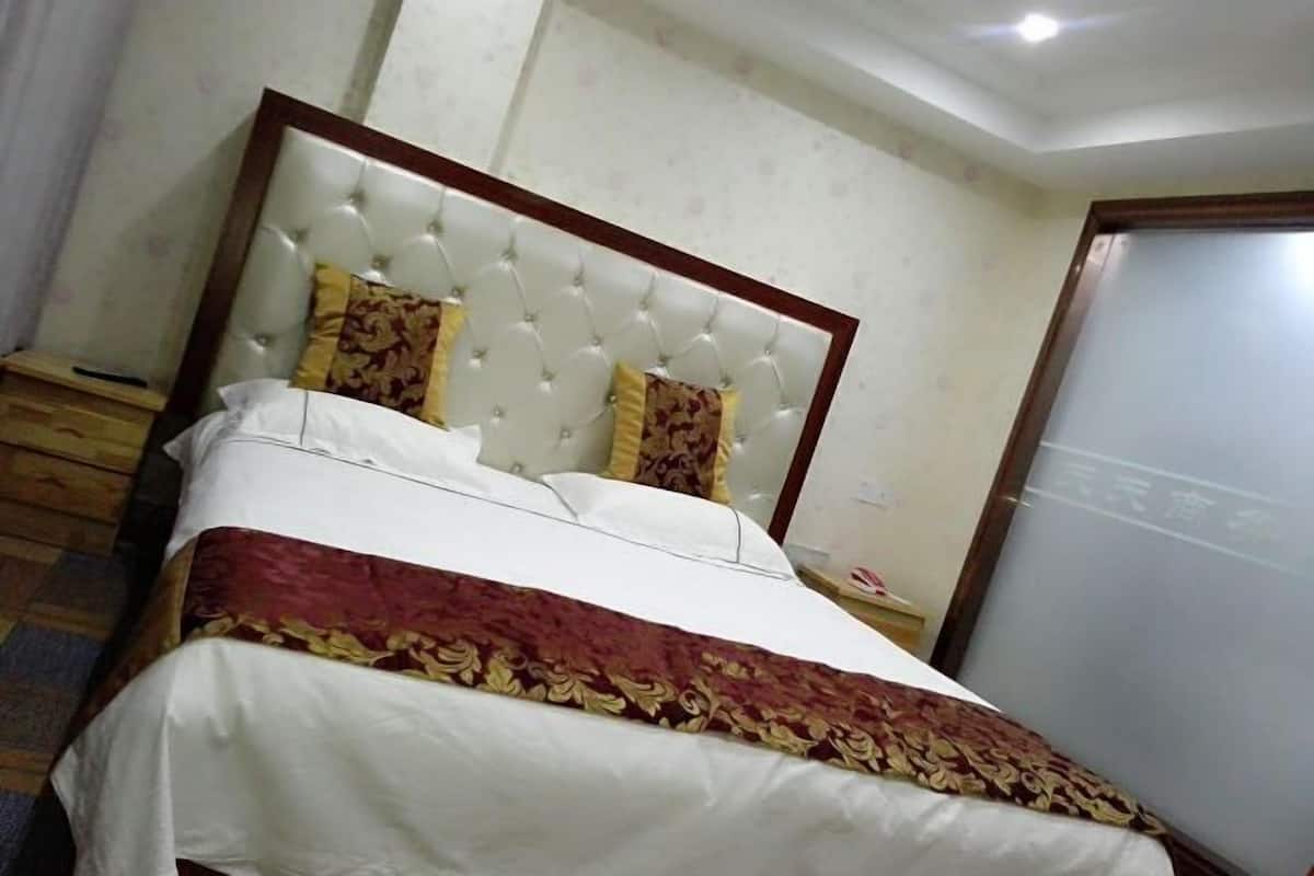 A neatly made bed with a tufted headboard, a patterned bedspread, and two decorative pillows.