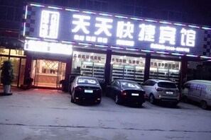 A building with a sign that reads '天天快宾é¦' and a parking lot with several cars. - Taihe Tiantian Express Hotel (Taihe)