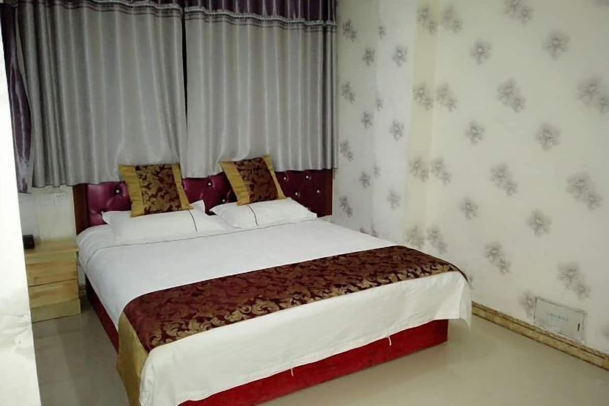 A bedroom with a bed, curtains, and patterned wallpaper.