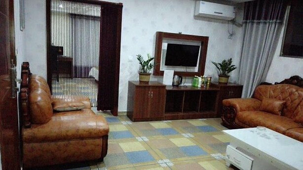 A living room with a sofa, a television, a cabinet, and a patterned floor. - Taihe Tiantian Express Hotel (Taihe)