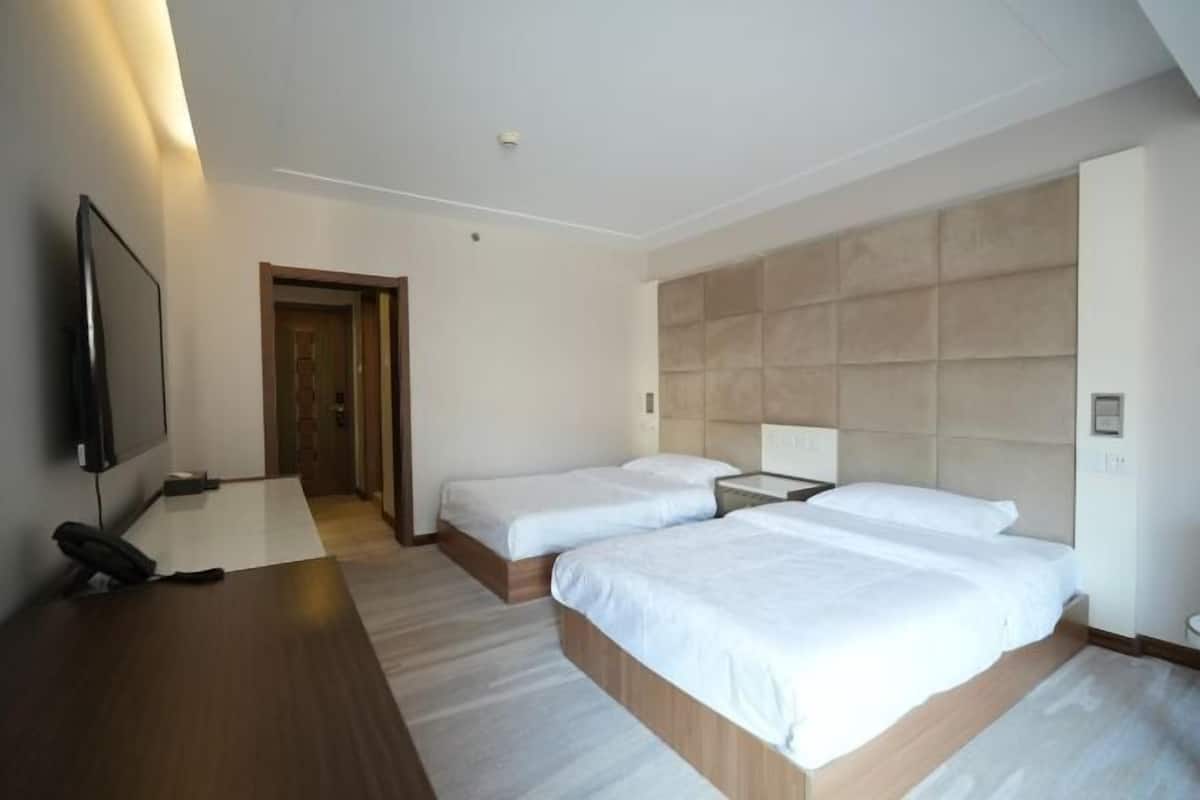 Ein Hotelzimmer mit zwei Betten, einem Schreibtisch mit Telefon und einem Fernseher.