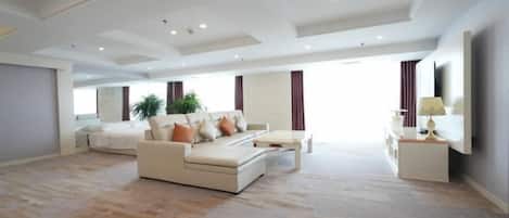 A spacious living room with a sofa set, a coffee table, and a TV on a stand.
