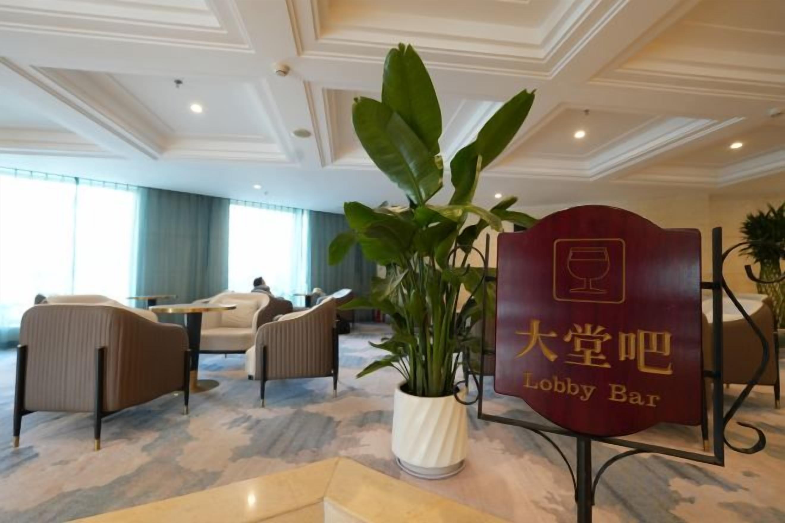 A lobby area with seating, a potted plant, and a sign for the lobby bar.