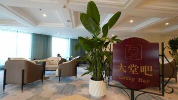 A lobby area with seating, a potted plant, and a sign for the lobby bar.