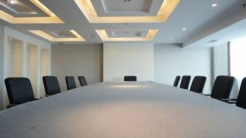 Une salle de conférence avec une longue table et de nombreuses chaises, un éclairage encastré et un mur sobre.