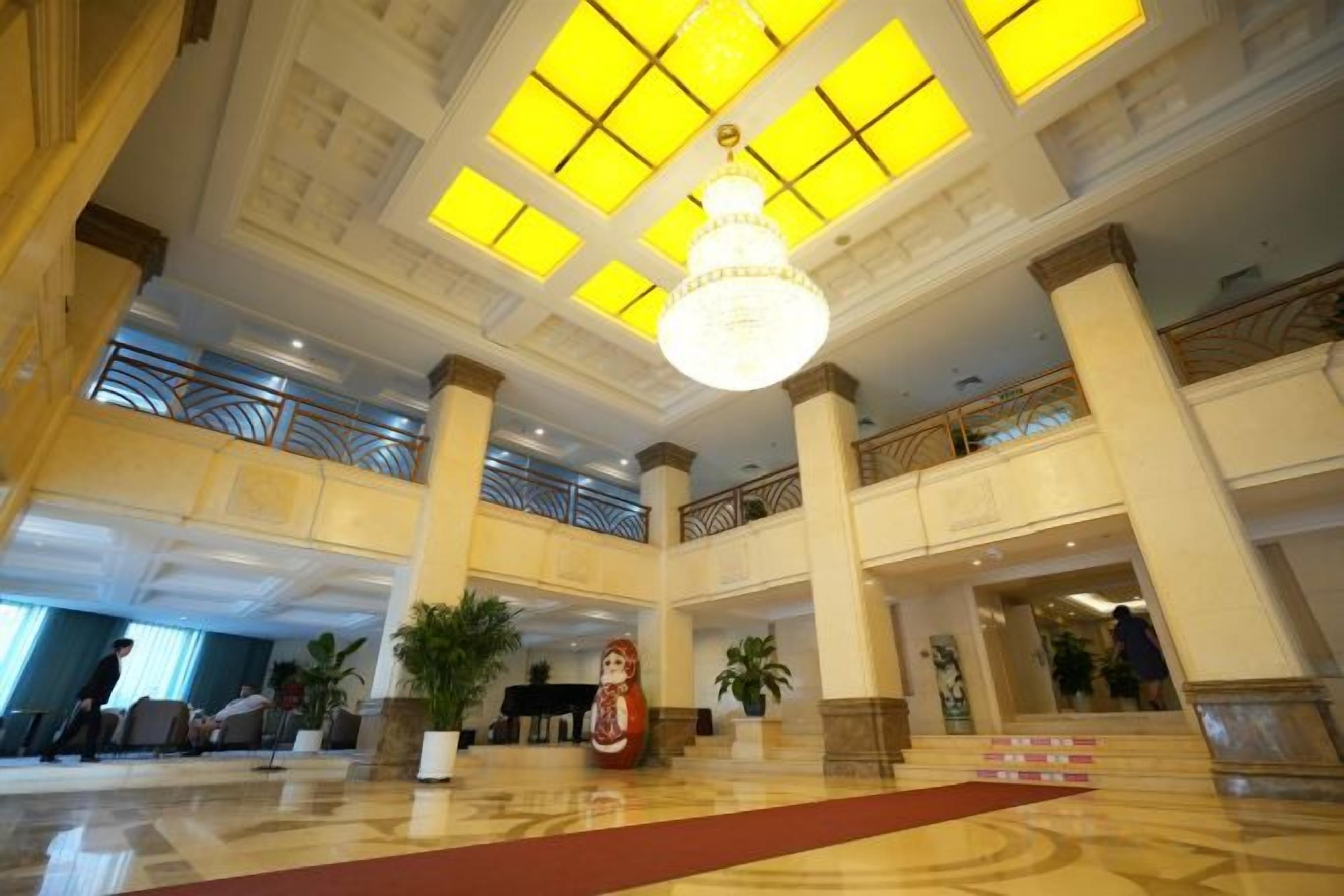 A spacious lobby with high ceilings, large windows, and a central chandelier.