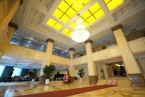 A spacious lobby with high ceilings, large windows, and a central chandelier. - Tumenjiang Business Hotel (Hunchun)