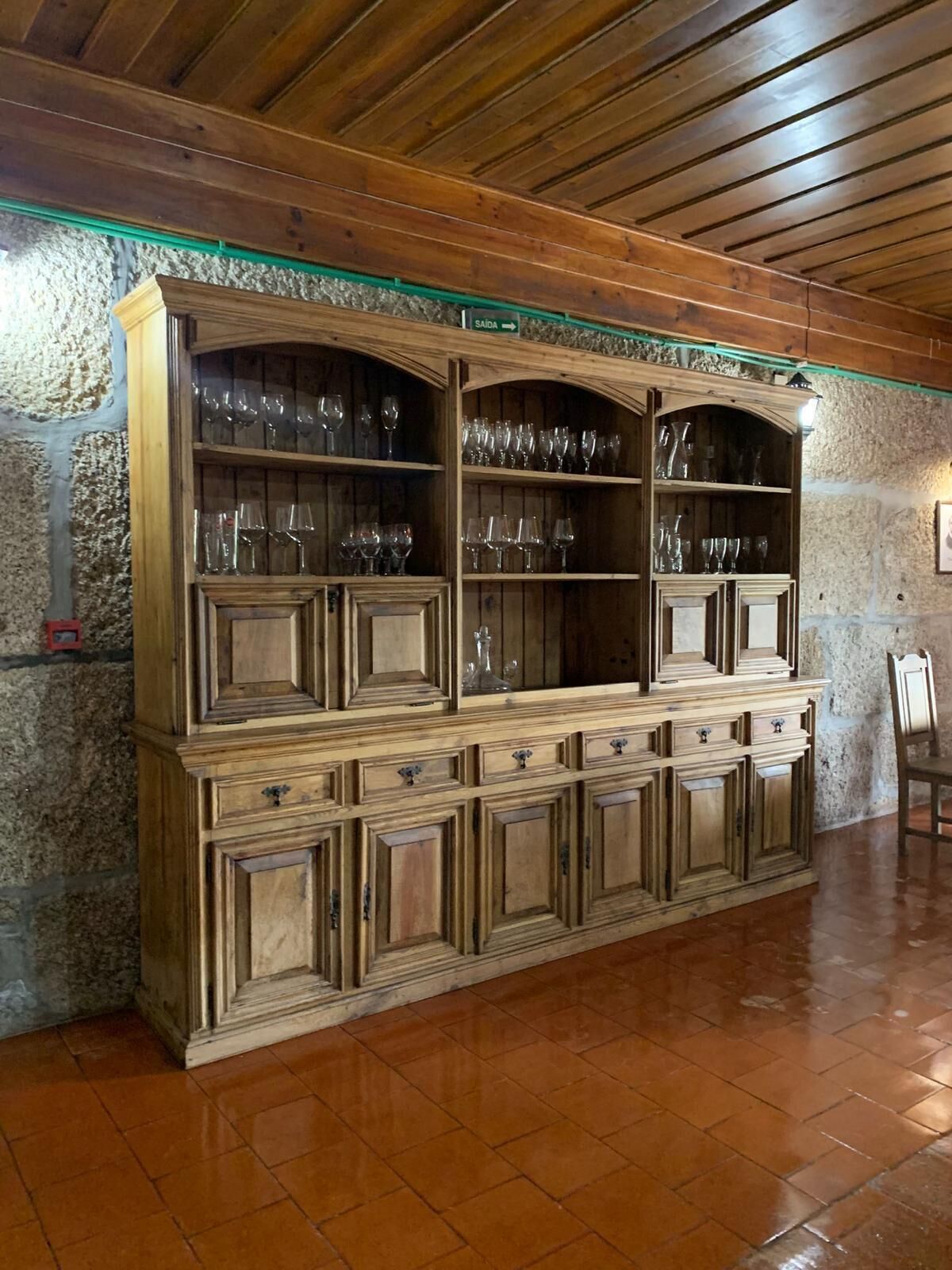 Un mueble de madera con varios estantes y cajones, probablemente utilizado para guardar vasos y otros objetos.