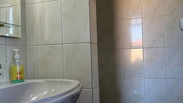 Un bagno con un lavandino bianco, uno specchio e una bottiglia di sapone per le mani.