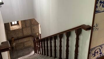 Una escalera con barandilla de madera y un muro de piedra en la parte inferior.