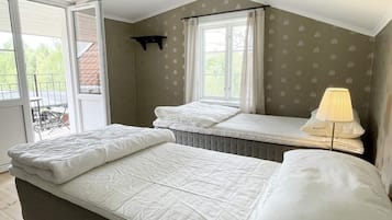 Un dormitorio con una cama, una ventana con cortinas, un estante pequeño y una lámpara.