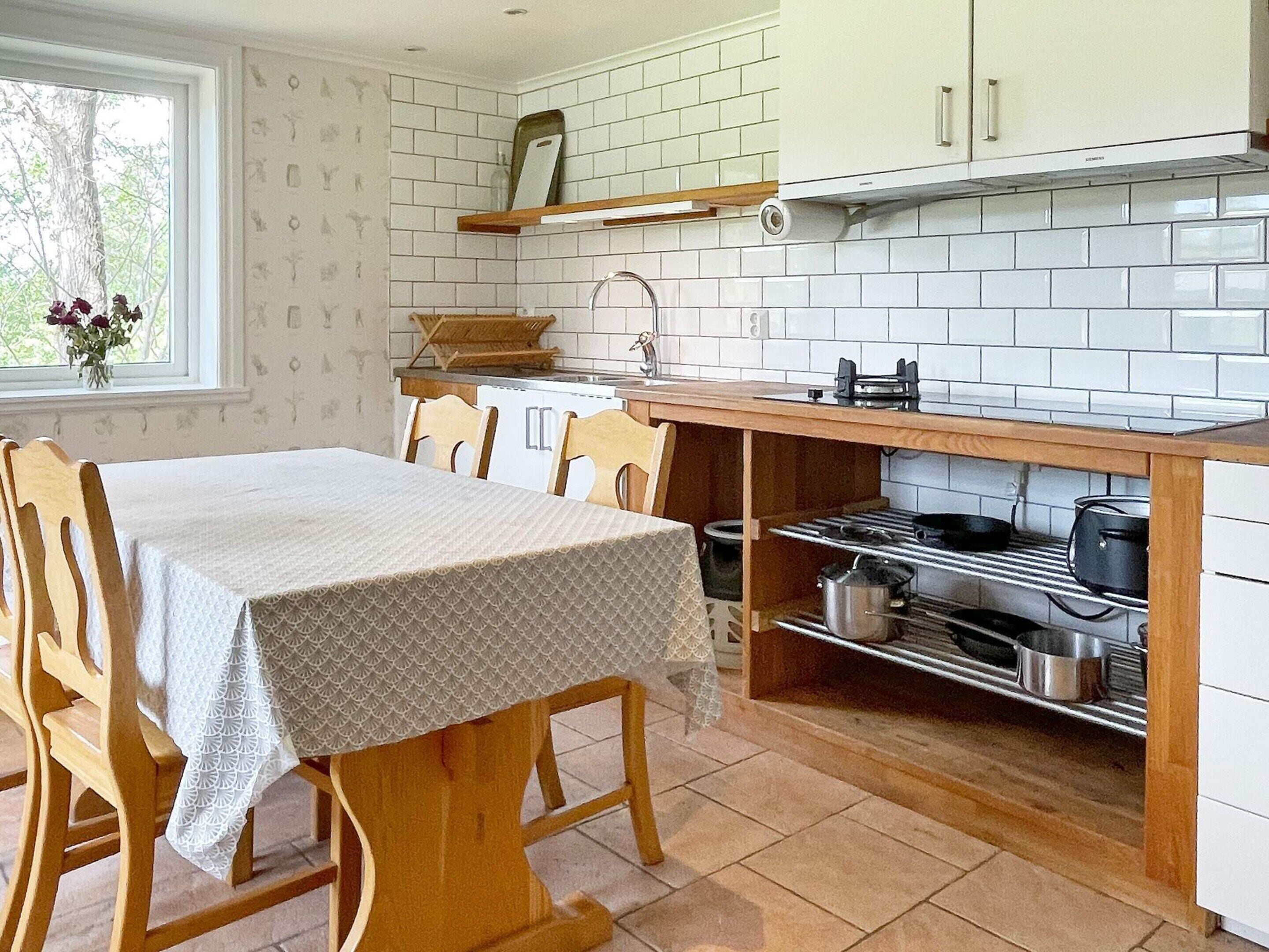 Una cocina con una mesa de comedor, sillas, estufa y pileta.