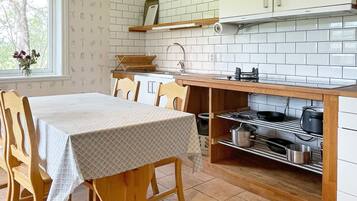 Una cocina con una mesa de comedor, sillas, estufa y pileta.