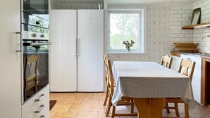 Uma cozinha com mesa, cadeiras e janela com vista para árvores.