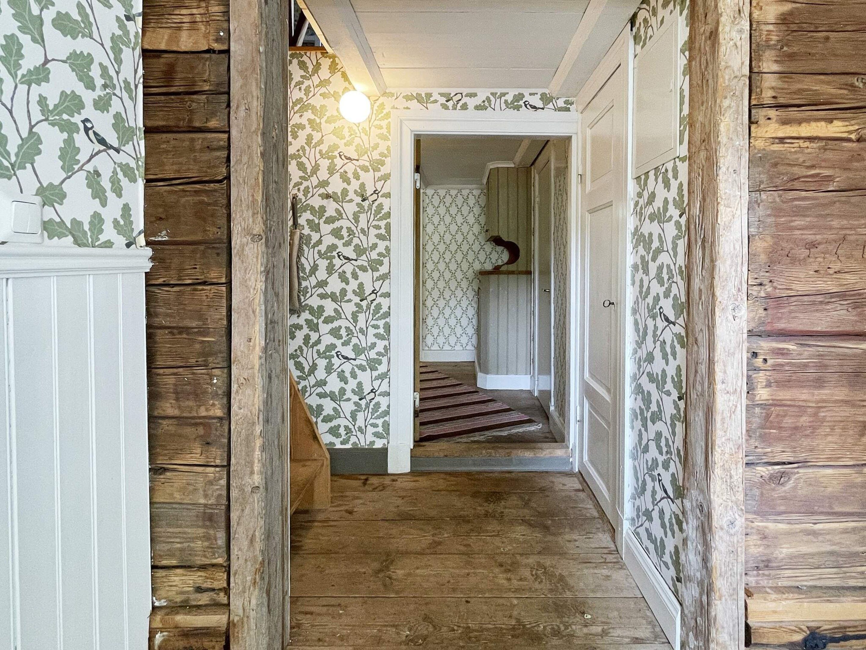 A wooden staircase leading to a room with patterned wallpaper and a bird decoration.