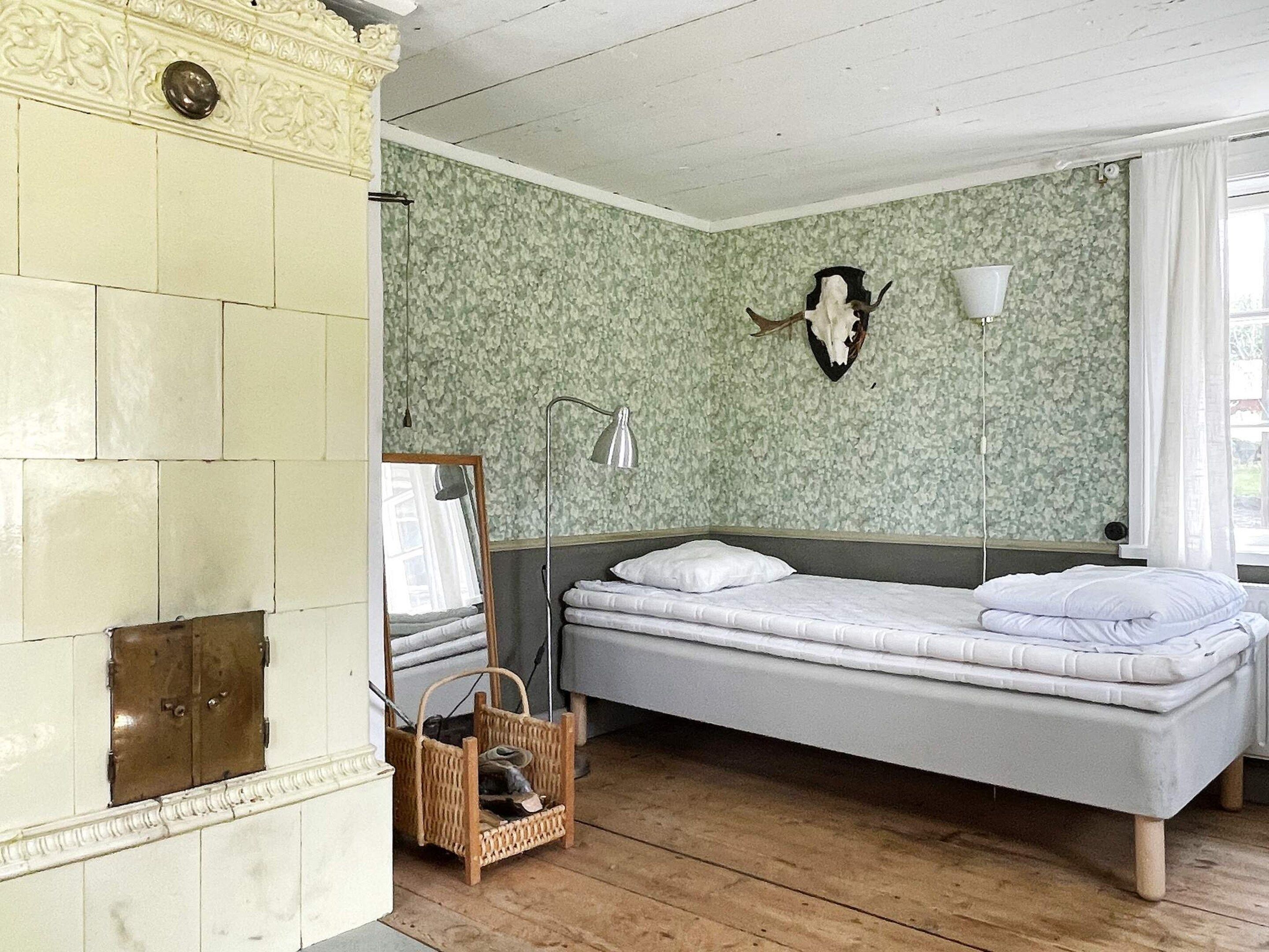 A room with a bed, a mirror, a wall-mounted lamp, and a decorative skull on the wall.