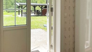 Abertura de porta que dá para área externa com mesa de piquenique e área de estar coberta.