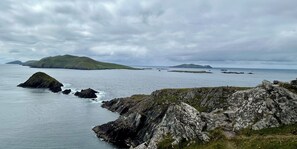A coastal landscape with rocky terrain and distant islands under a cloudy sky. - 4 Bedroom Detached Home Close to Kenmare Town (Kenmare)