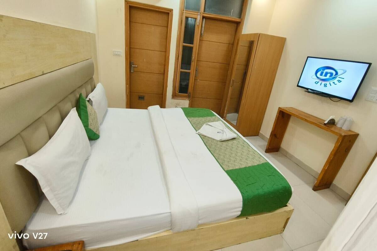 A hotel room with a bed, a TV, and wooden wardrobes.