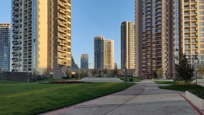 Una zona residencial moderna amb edificis d'apartaments alts, un passeig pavimentat i zones verdes.
