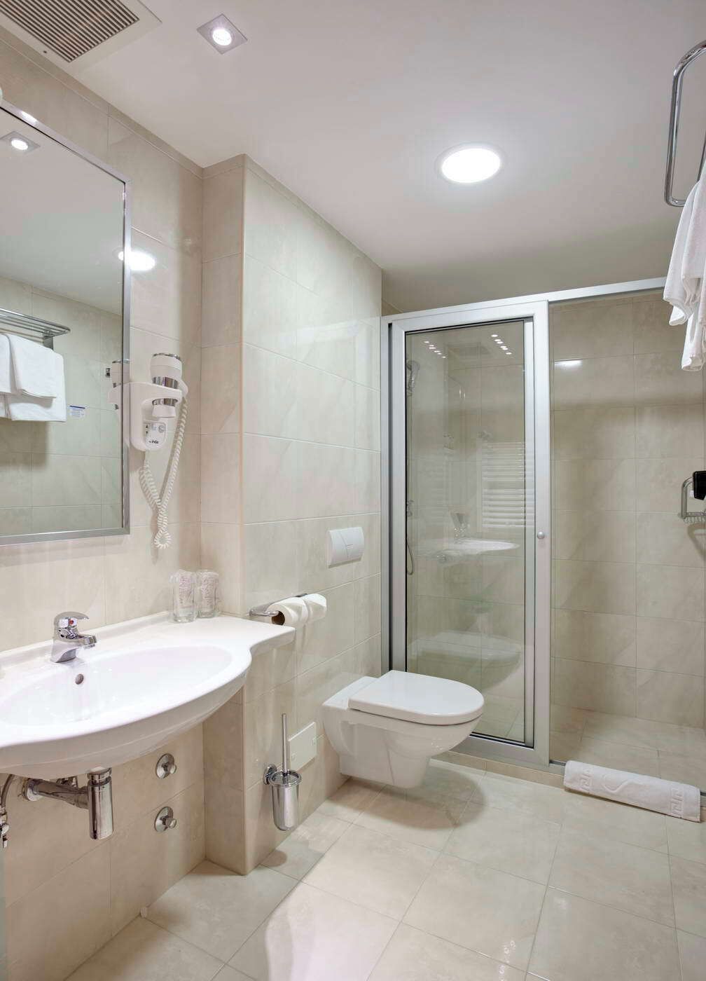 A modern bathroom with a large sink, toilet, and glass shower enclosure.