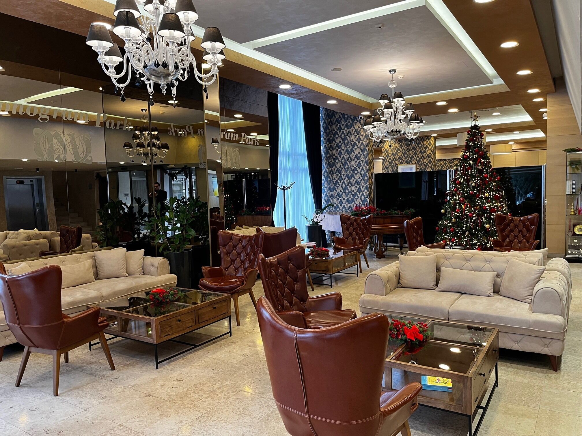 A spacious lobby with leather sofas, a glass coffee table, and a large Christmas tree.