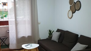 A living room with a dark brown sofa, a small white table, and a potted plant.