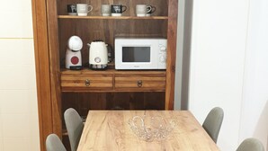 A wooden dining table with a crown-shaped centerpiece, a white microwave, and a coffee maker on a wooden shelf above.