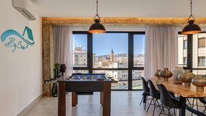 Een moderne eetruimte met een tafelvoetbalspel, een houten eettafel en zwarte stoelen.