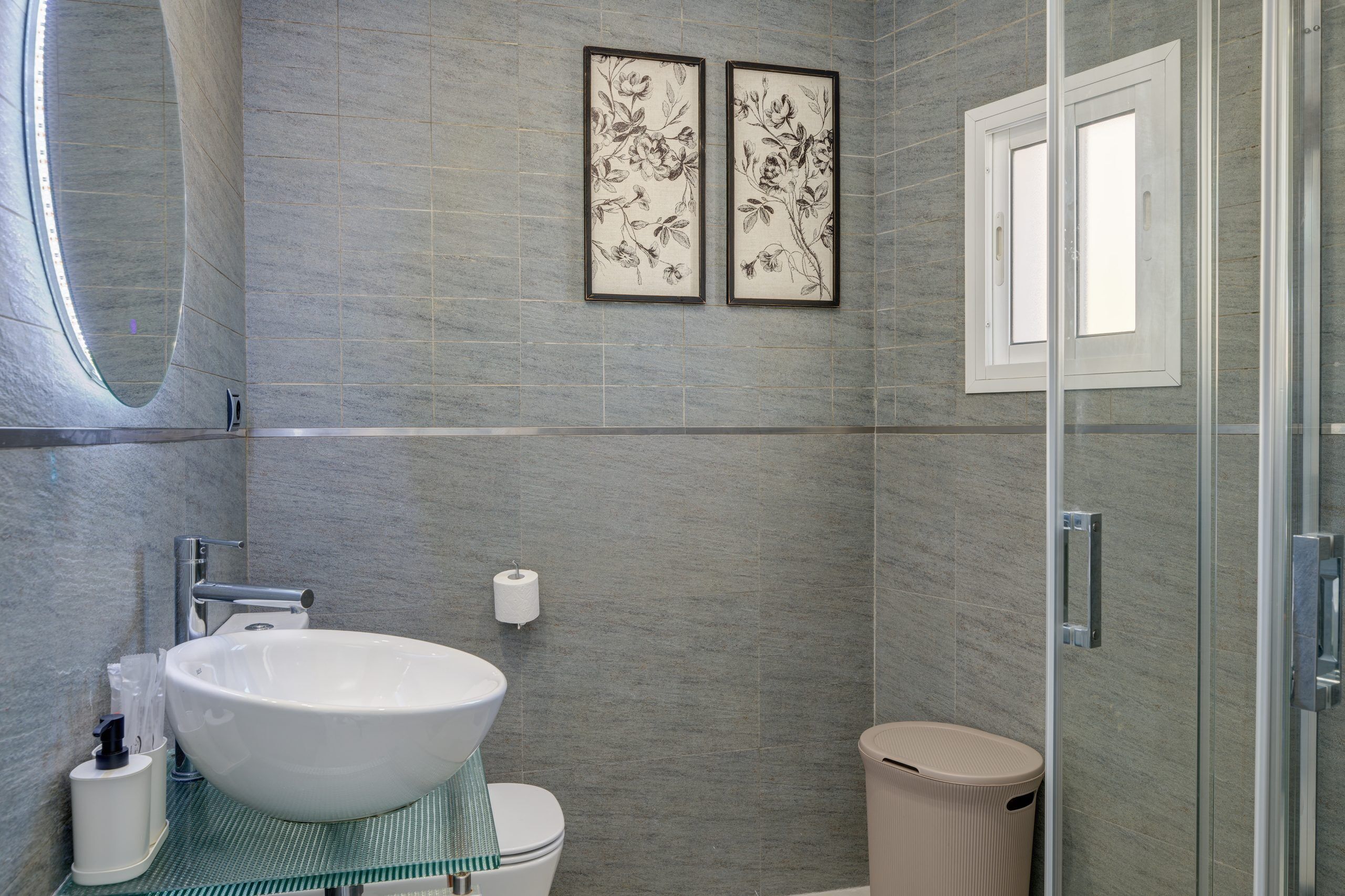 A modern bathroom with a large sink, toilet, and a glass shower enclosure.