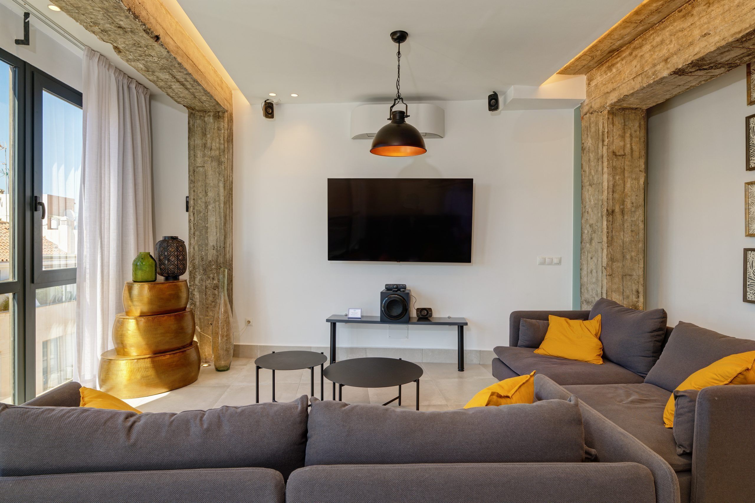 Een moderne woonkamer met een grijze bank, een salontafel en een aan de muur bevestigde televisie.