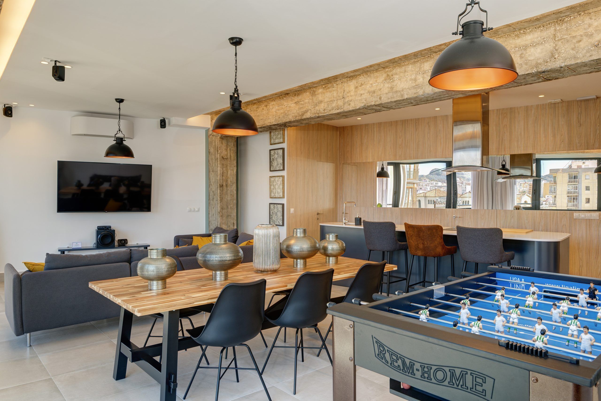 A modern living room with a foosball table, a wooden dining table, and a sofa.