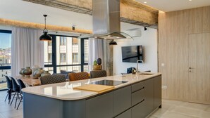 Een moderne keuken met een groot schiereiland, inbouwapparatuur en een eethoek met uitzicht.