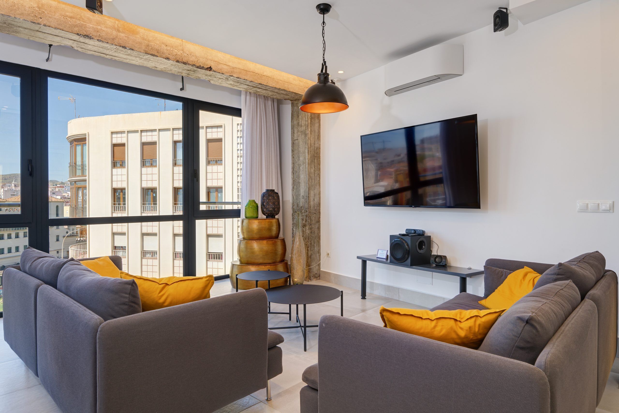 A modern living room with a large window, a flat-screen TV, and a coffee table.