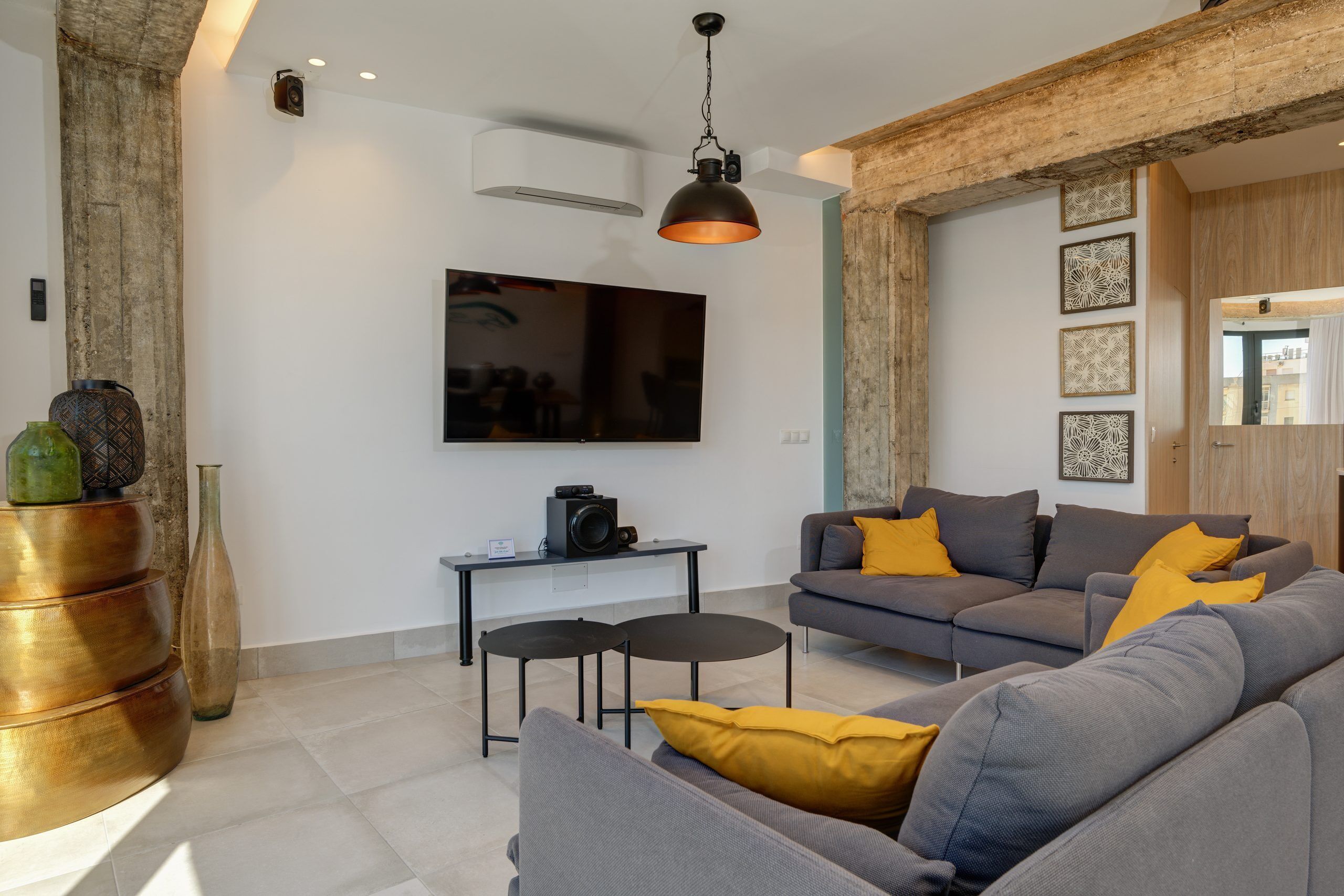 A modern living room with a grey sofa, a coffee table, and a television mounted on the wall.