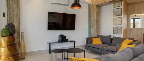 A modern living room with a grey sofa, a coffee table, and a television mounted on the wall.