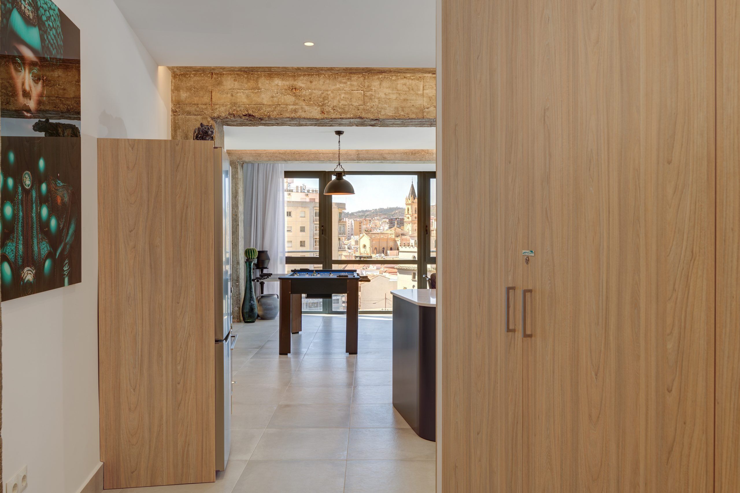 Un intérieur moderne avec un plancher en bois, un coin repas comprenant une table et des chaises, et une vue sur les bâtiments à travers de grandes fenêtres.