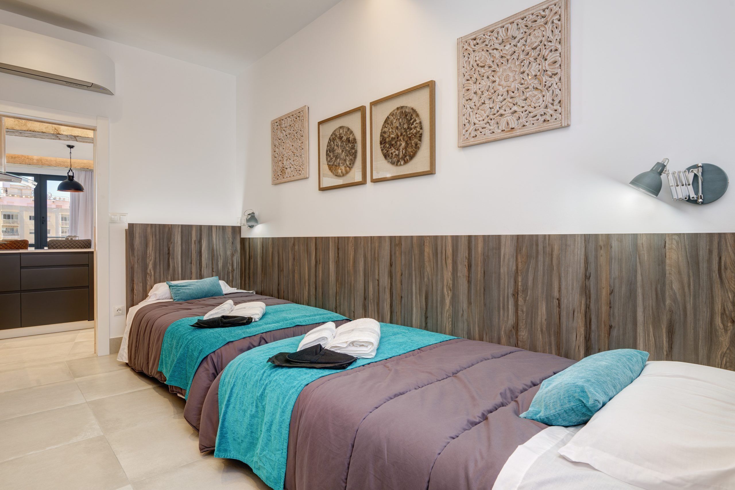 A hotel room with two beds, a wooden headboard, and three wall-mounted artworks.